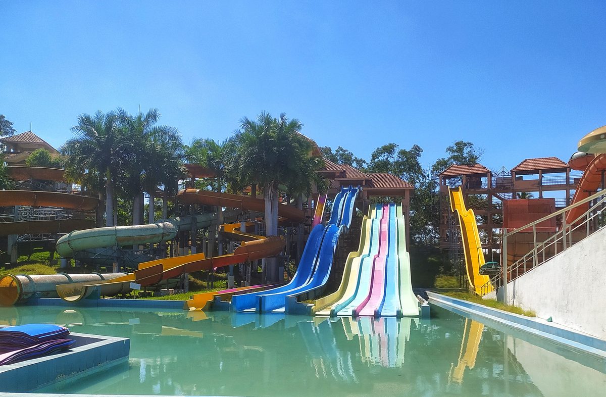 Colourful multi-lane water slides and slide towers above a pool at Athisayam water park, Paravai, Madurai
