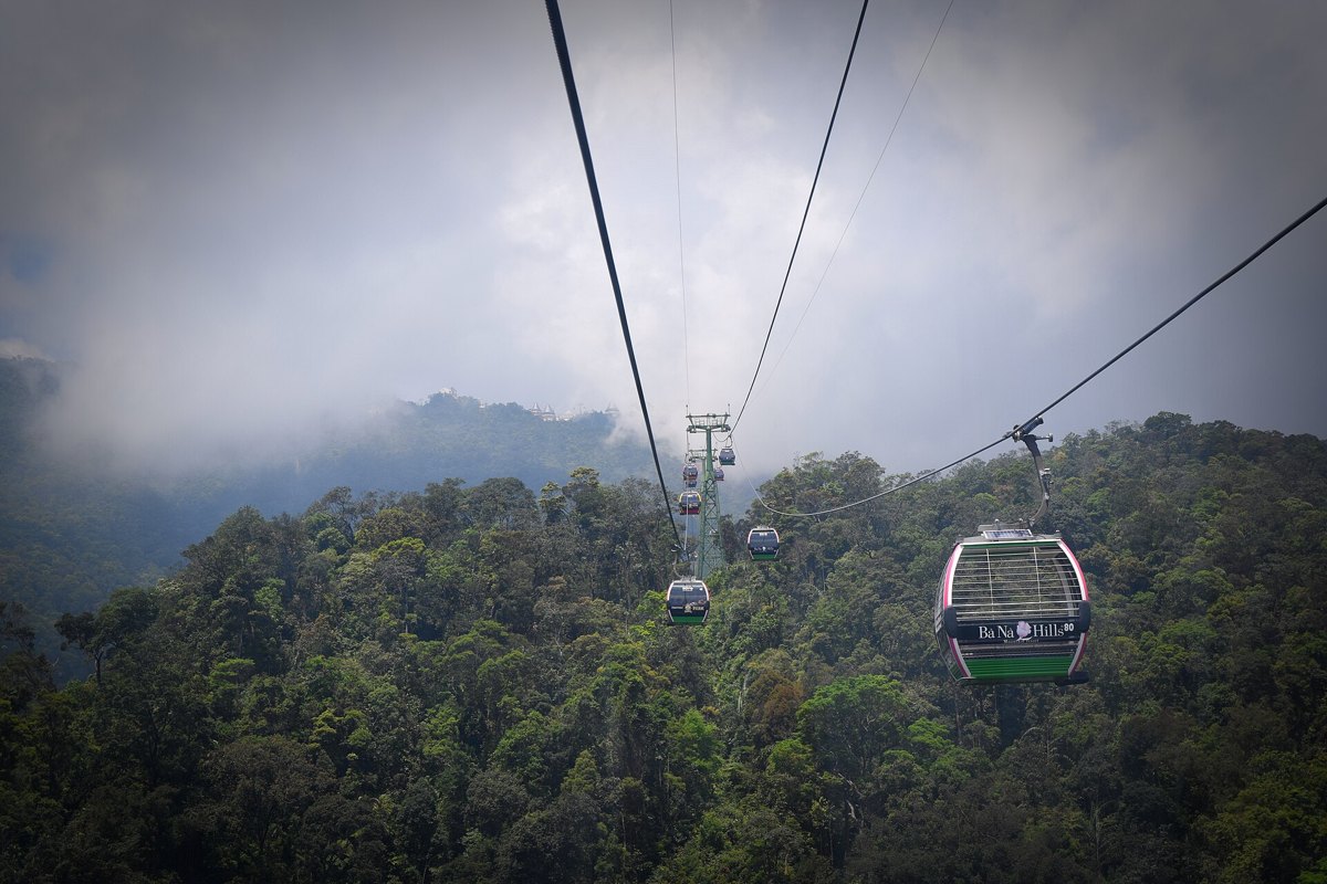 Ba Na Hills Ticket Price: Cable Car, Golden Bridge Access and Buffet Combos Explained Ba Na Hills cable car cabins gliding over thick green forest towards the misty summit, Da Nang, Vietnam