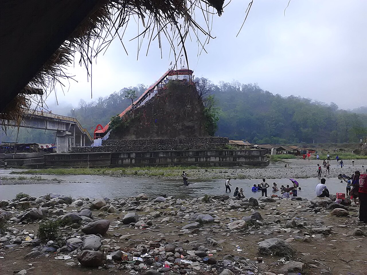 Garjiya Devi temple on a rock above the Kosi river near Ramnagar, with visitors on the riverbank