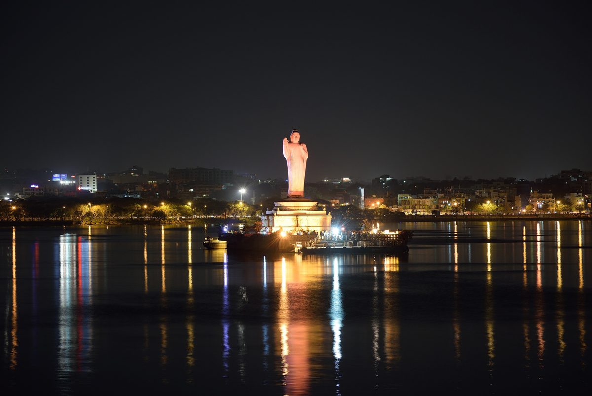 Hussain Sagar Boating Ticket Price: Lumbini Park Boats, Timings and the Buddha Statue Ride Illuminated monolithic Buddha statue on its island in Hussain Sagar lake at night, with city lights reflected in the water, Hyderabad
