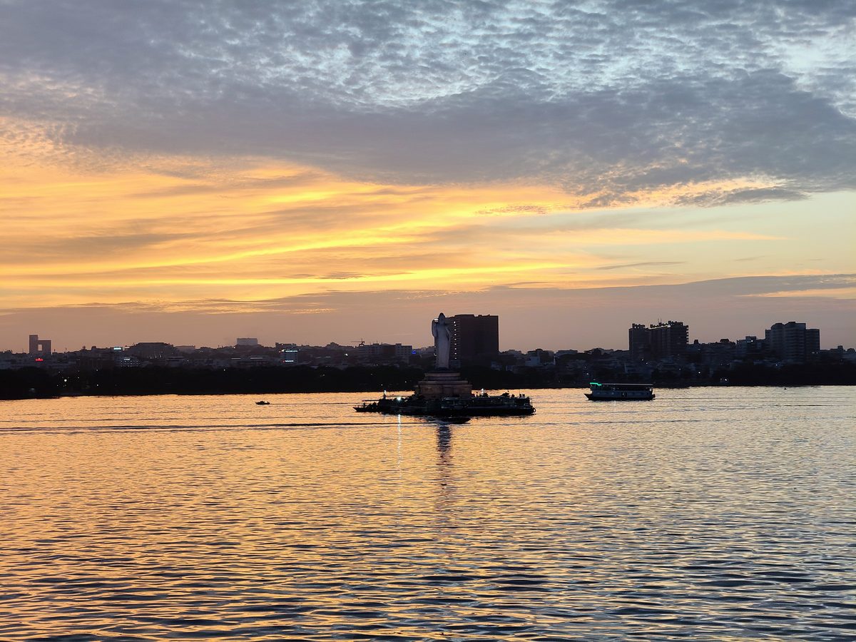Hussain Sagar Boating Ticket Price: Lumbini Park Boats, Timings and the Buddha Statue Ride Sunset sky over Hussain Sagar lake in Hyderabad with the Buddha statue island and a boat in silhouette