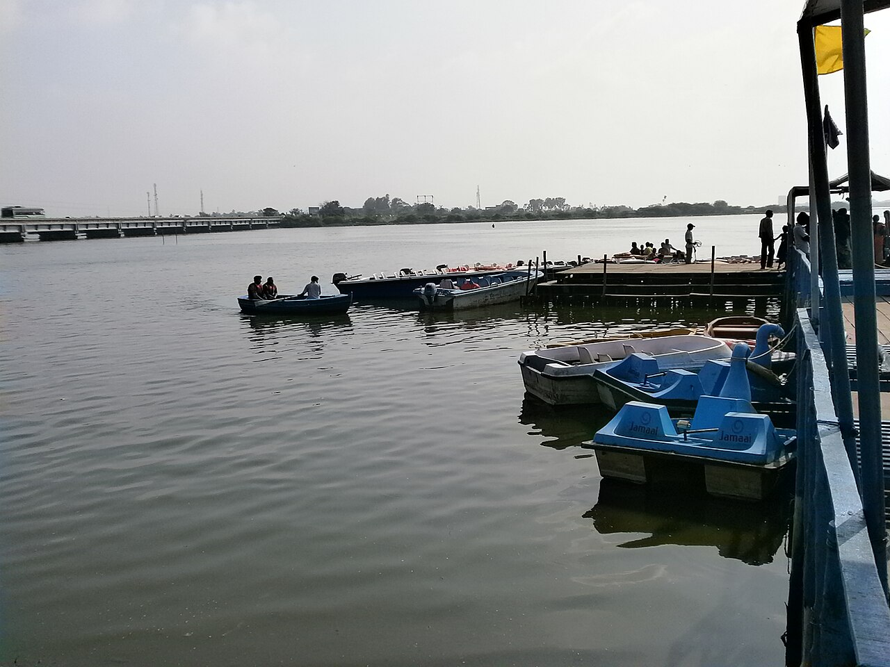 Floating jetty at Muttukadu with blue pedal boats and motor boats tied up and the backwater stretching to the horizon