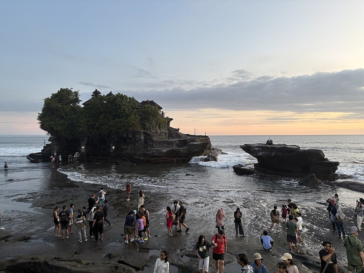 Visitors on the exposed rocks in front of the Tanah Lot temple rock at sunset, Bali
