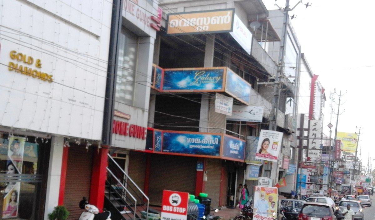 Flora Fantasia Amusement Park Ticket Price 2026: Rates, Timings, Rides and How to Reach (Valanchery, Malappuram) Busy main street in Valanchery town, Malappuram, with shop signs and buildings on both sides